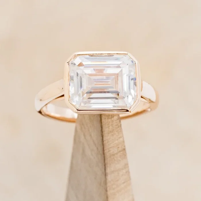 “EDITH” – EMERALD CUT MOISSANITE SOLITAIRE ENGAGEMENT RING WITH DIAMOND ACCENTS