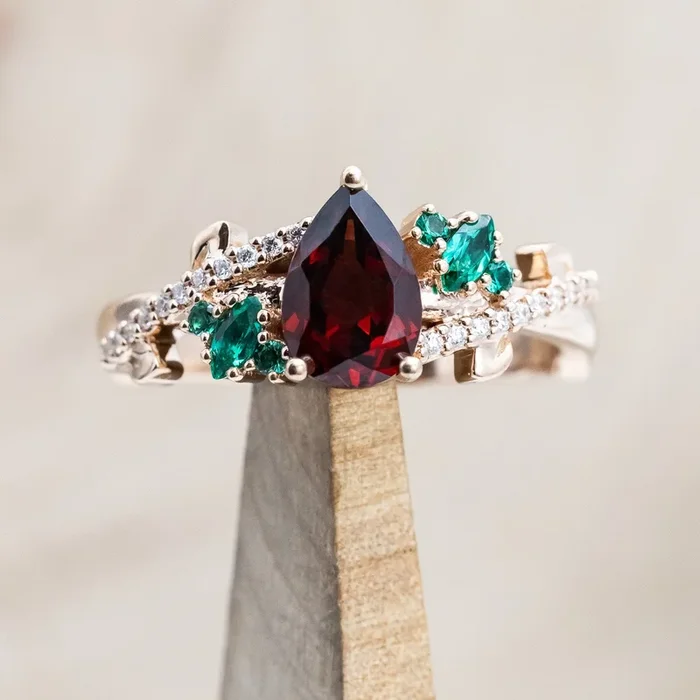 “KAMILA” – PEAR CUT MOZAMBIQUE GARNET ENGAGEMENT RING WITH LAB-GROWN EMERALD & DIAMOND ACCENTS